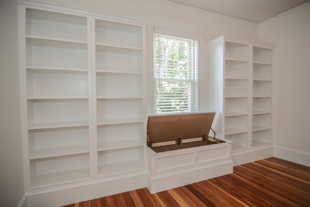 Diseño de despacho tradicional renovado de tamaño medio con biblioteca, paredes blancas, suelo de madera en tonos medios y escritorio independiente