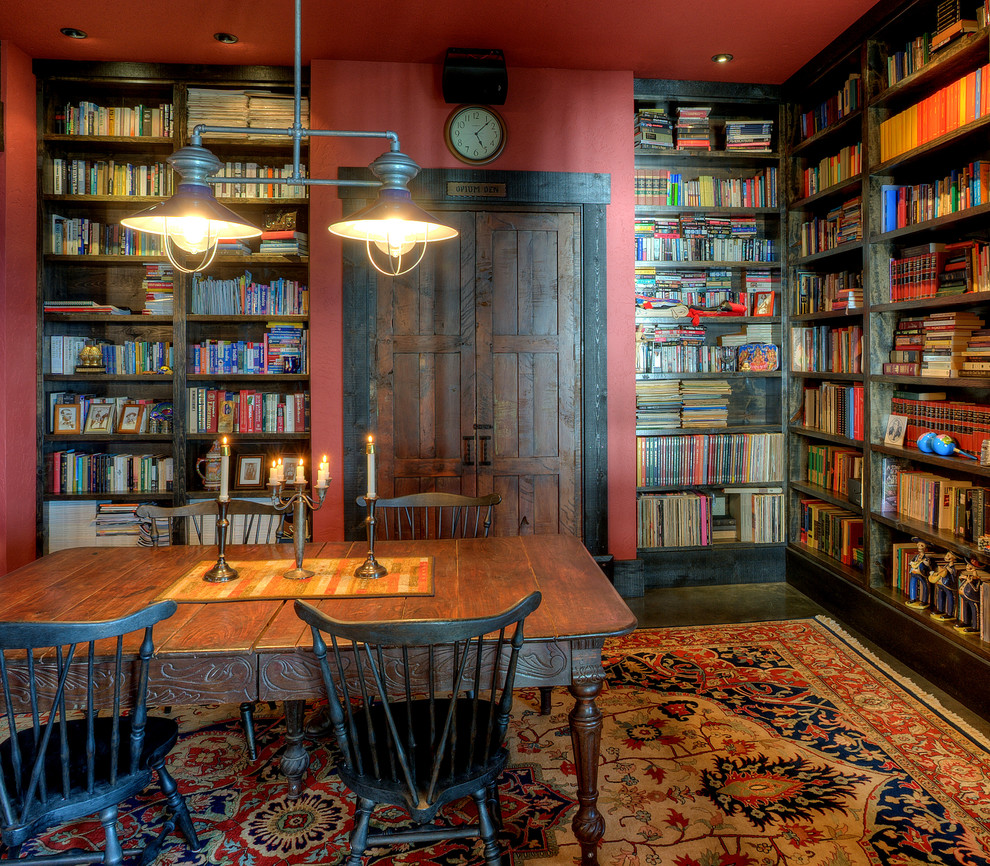 Foto di uno studio stile rurale con pareti rosse, scrivania autoportante, parquet scuro e libreria