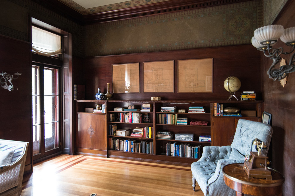 Foto de despacho clásico de tamaño medio sin chimenea con paredes marrones, suelo de madera clara, escritorio independiente y suelo marrón