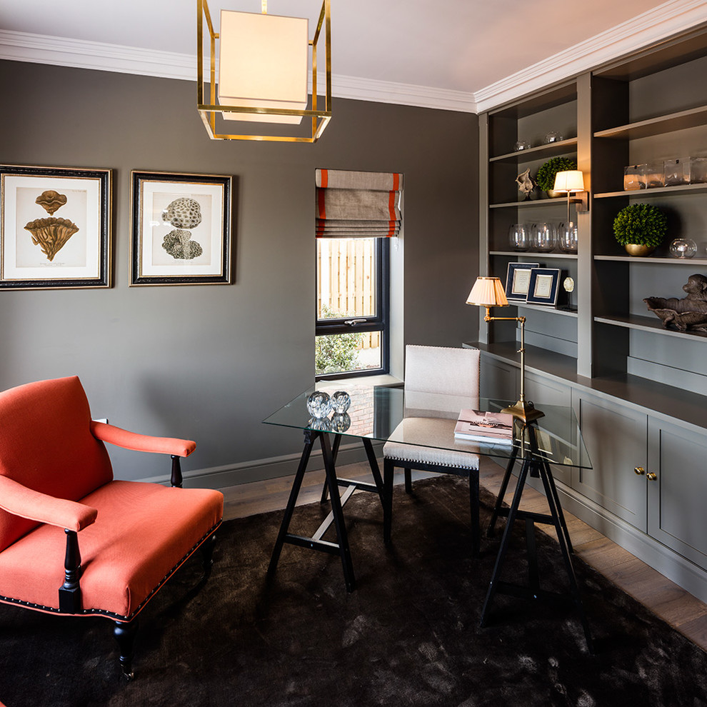 Mittelgroßes Klassisches Arbeitszimmer mit grauer Wandfarbe, braunem Holzboden und freistehendem Schreibtisch in Sonstige