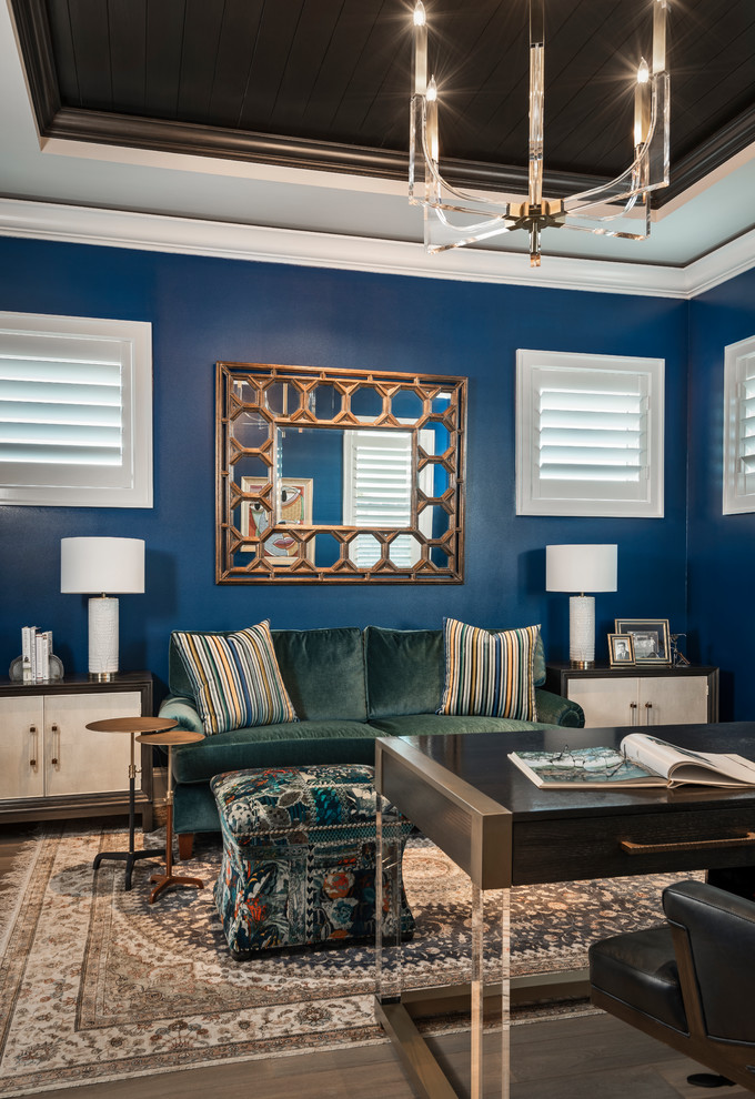 Mittelgroßes Klassisches Arbeitszimmer mit Arbeitsplatz, blauer Wandfarbe, braunem Holzboden, freistehendem Schreibtisch und braunem Boden in Sonstige