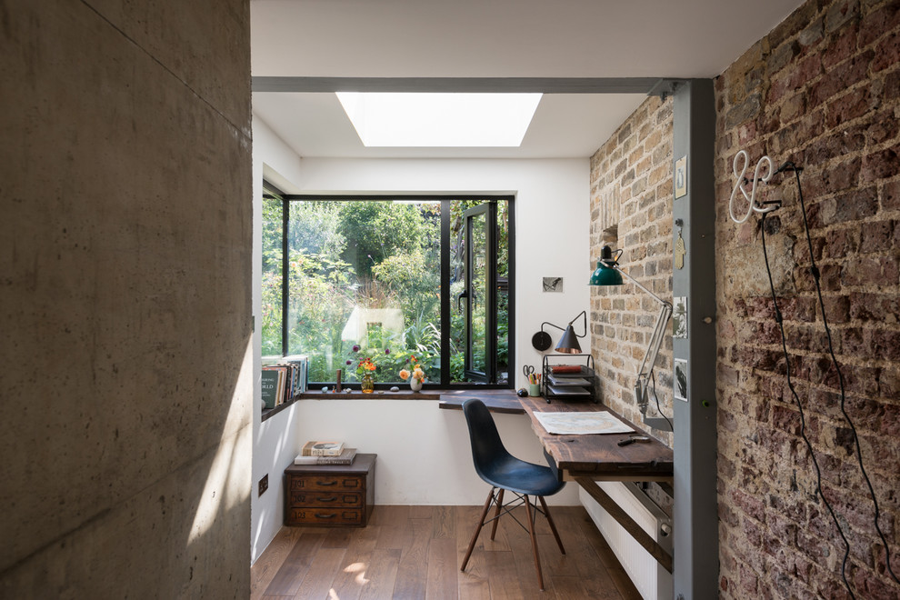 Urban home office in London with white walls, dark hardwood flooring and a built-in desk.