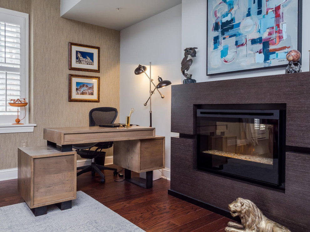 Imagen de despacho clásico renovado con paredes beige, suelo de madera oscura, chimenea lineal, escritorio independiente y papel pintado
