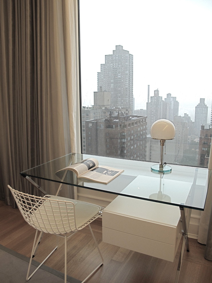 Photo of a small modern study in New York with light hardwood flooring, a freestanding desk, white walls and brown floors.