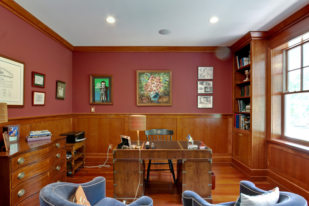 Foto de despacho clásico renovado de tamaño medio sin chimenea con paredes rojas, suelo de madera en tonos medios y escritorio independiente