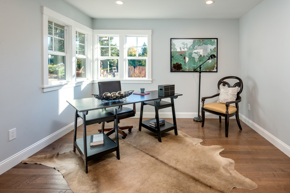 Modelo de despacho de estilo de casa de campo de tamaño medio sin chimenea con suelo de madera en tonos medios, escritorio independiente, paredes azules y suelo beige