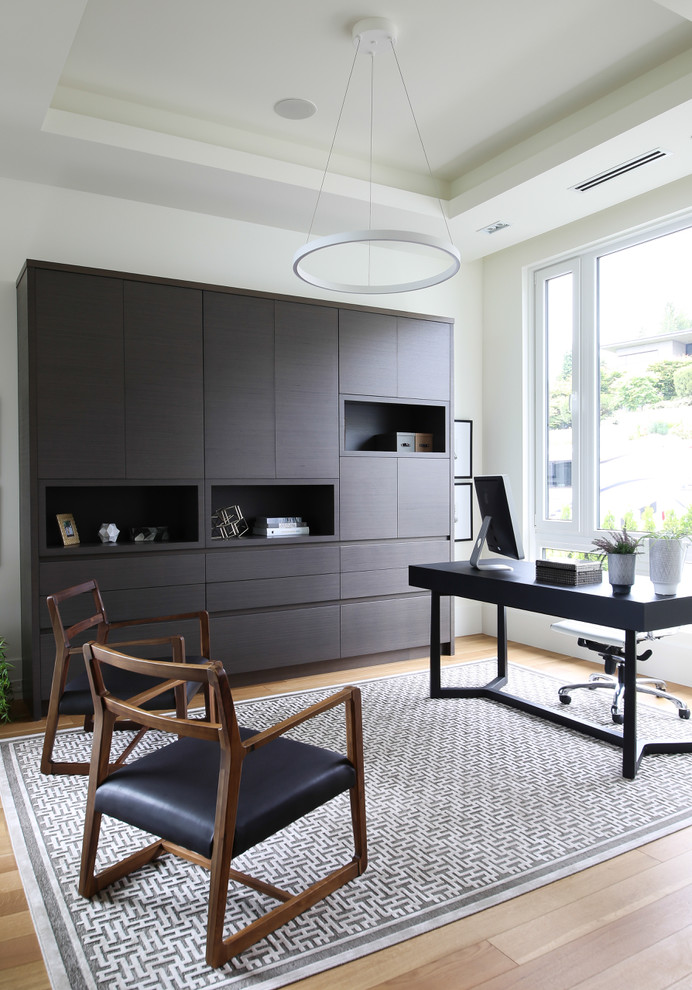 Modernes Arbeitszimmer mit beiger Wandfarbe, hellem Holzboden und freistehendem Schreibtisch in Vancouver