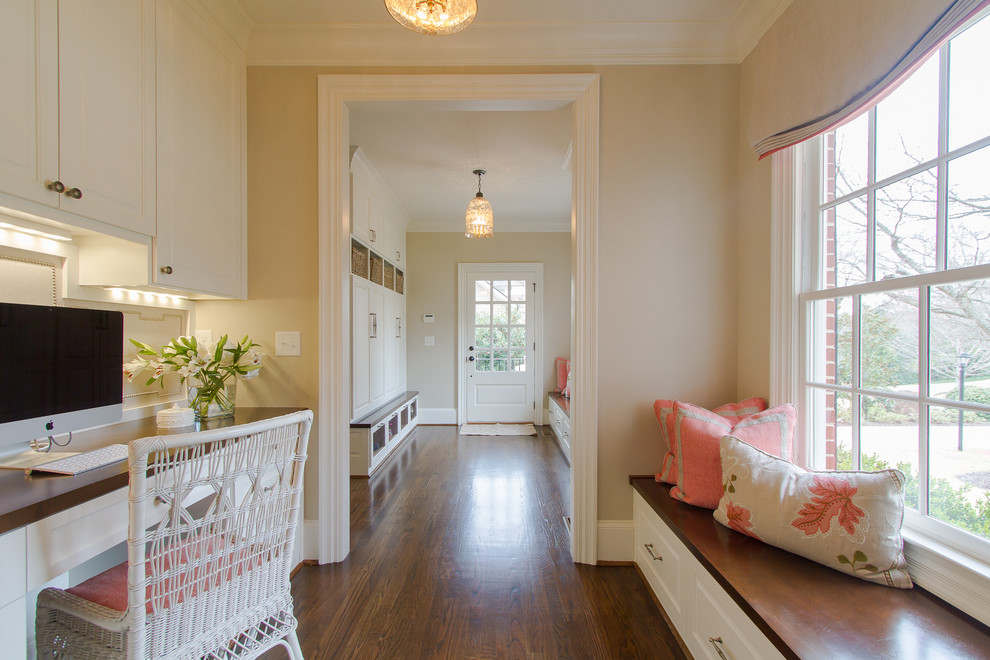 Elegant built-in desk brown floor home office photo in Atlanta with beige walls