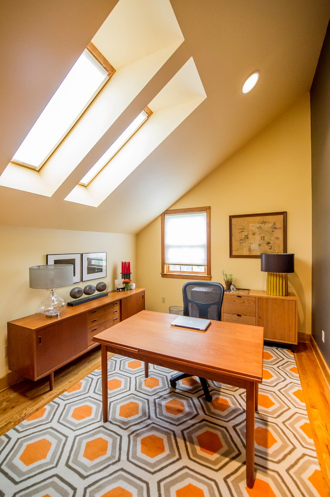 Immagine di uno studio moderno di medie dimensioni con pareti gialle, pavimento in legno massello medio, nessun camino e scrivania autoportante