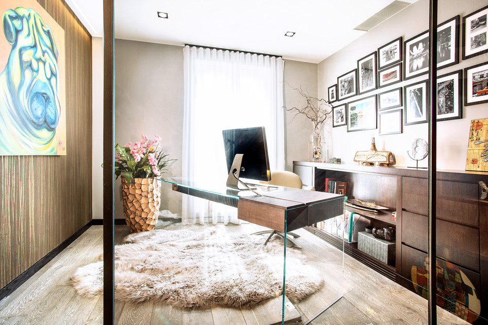 Modelo de despacho contemporáneo de tamaño medio con paredes beige, suelo de madera clara, escritorio independiente y suelo beige