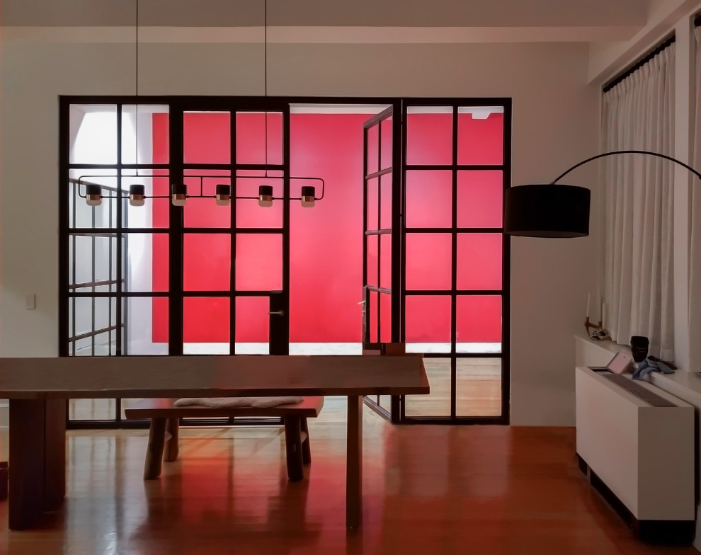 Mittelgroßes Modernes Arbeitszimmer mit Arbeitsplatz, roter Wandfarbe, dunklem Holzboden und braunem Boden in New York