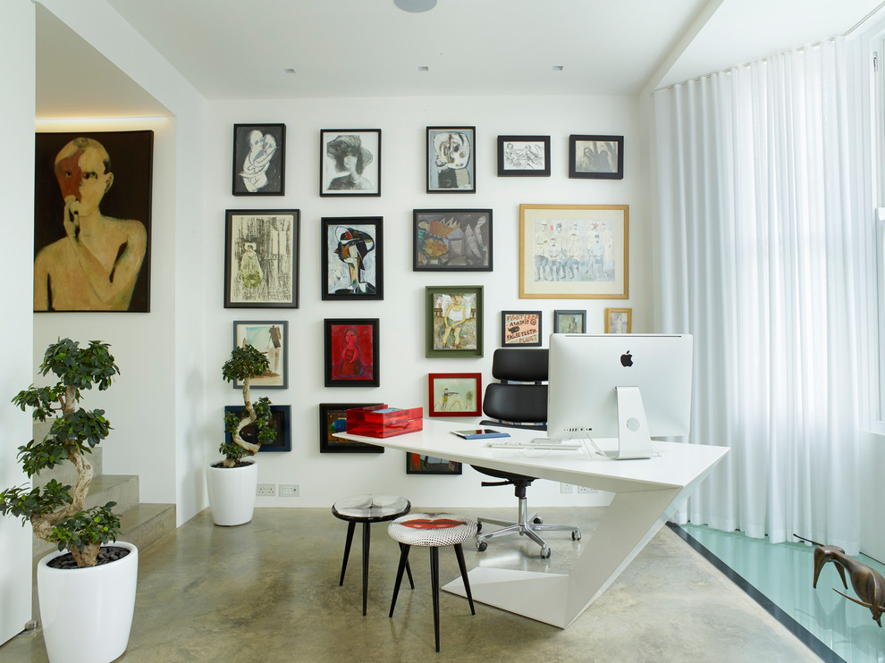 This is an example of a large contemporary study in London with white walls, concrete flooring, a freestanding desk, grey floors and no fireplace.