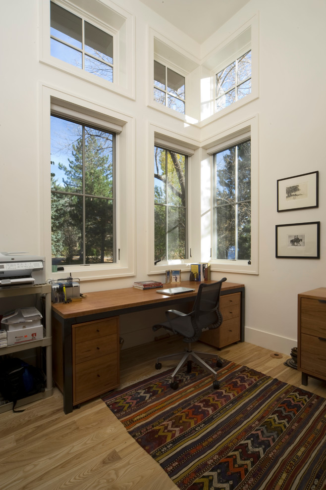 Inspiration för mellanstora lantliga hemmabibliotek, med vita väggar, ljust trägolv och ett fristående skrivbord