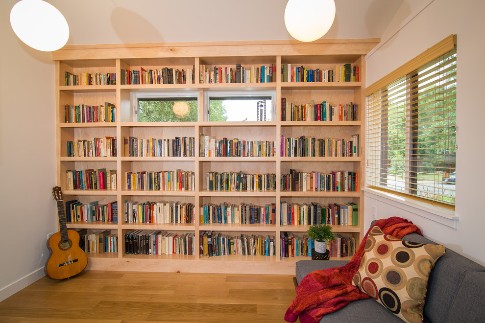 Foto på ett mellanstort 50 tals arbetsrum, med ett bibliotek, vita väggar och ljust trägolv