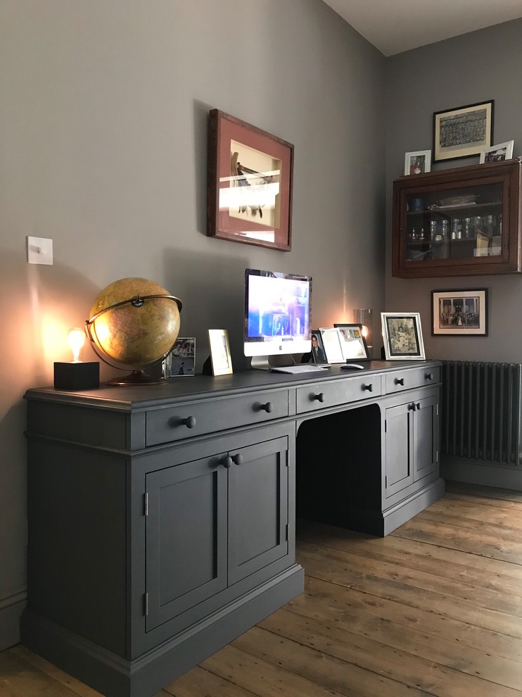 Foto de despacho romántico grande con paredes grises, suelo de madera en tonos medios, todas las chimeneas, marco de chimenea de metal, escritorio independiente y suelo marrón