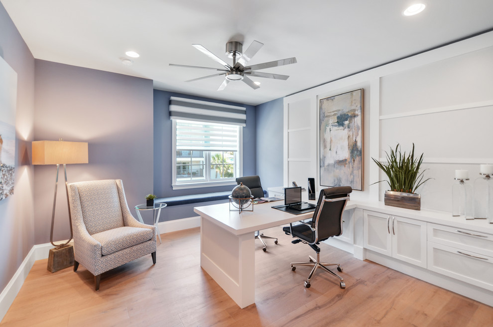 Example of a large built-in desk medium tone wood floor home office design in Miami with blue walls