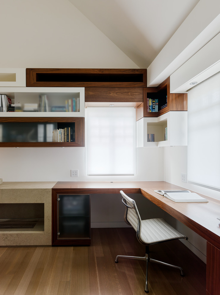 Idéer för ett modernt hemmabibliotek, med vita väggar, ett inbyggt skrivbord och ljust trägolv