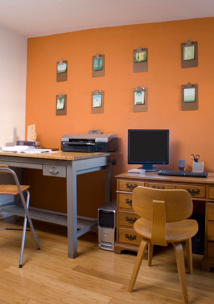 Пример оригинального дизайна: маленький кабинет в современном стиле с оранжевыми стенами, отдельно стоящим рабочим столом и светлым паркетным полом для на участке и в саду