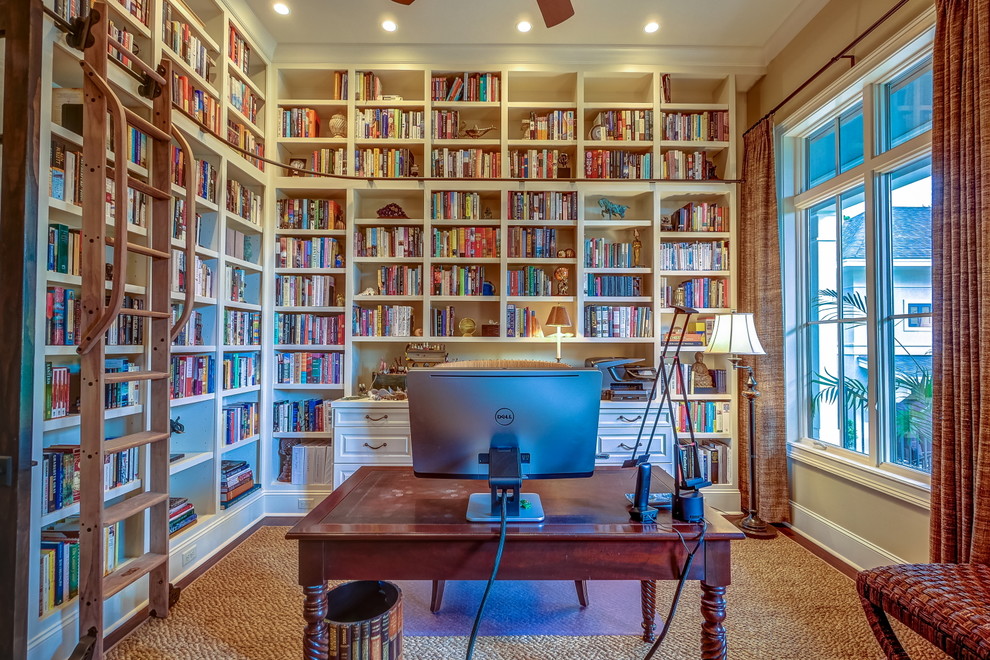 Esempio di uno studio tropicale con libreria, pavimento in legno massello medio e scrivania autoportante