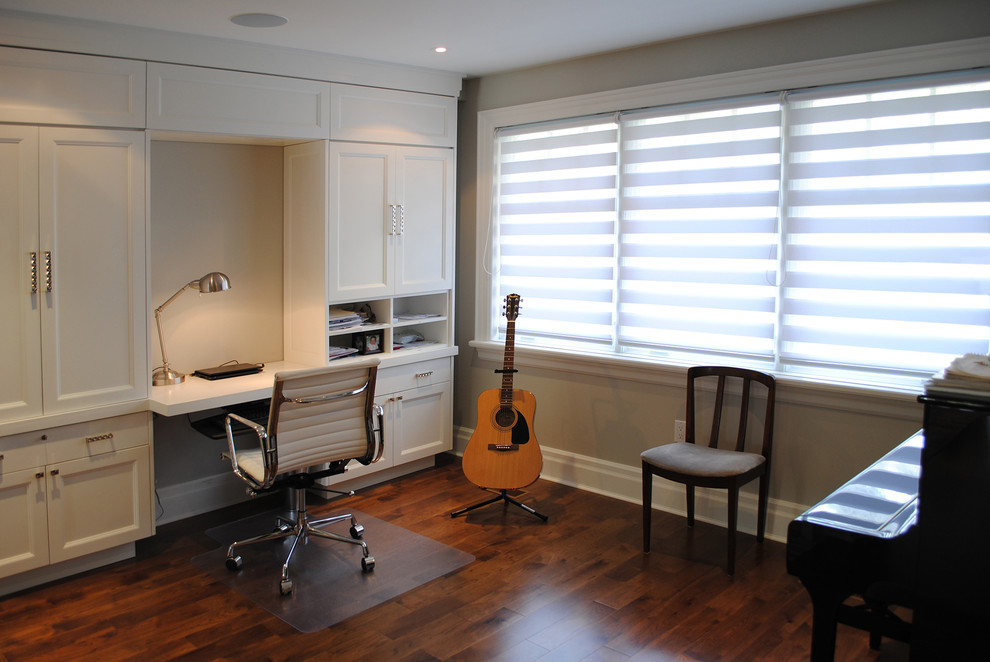 Modern inredning av ett hemmastudio, med grå väggar, mörkt trägolv och ett inbyggt skrivbord