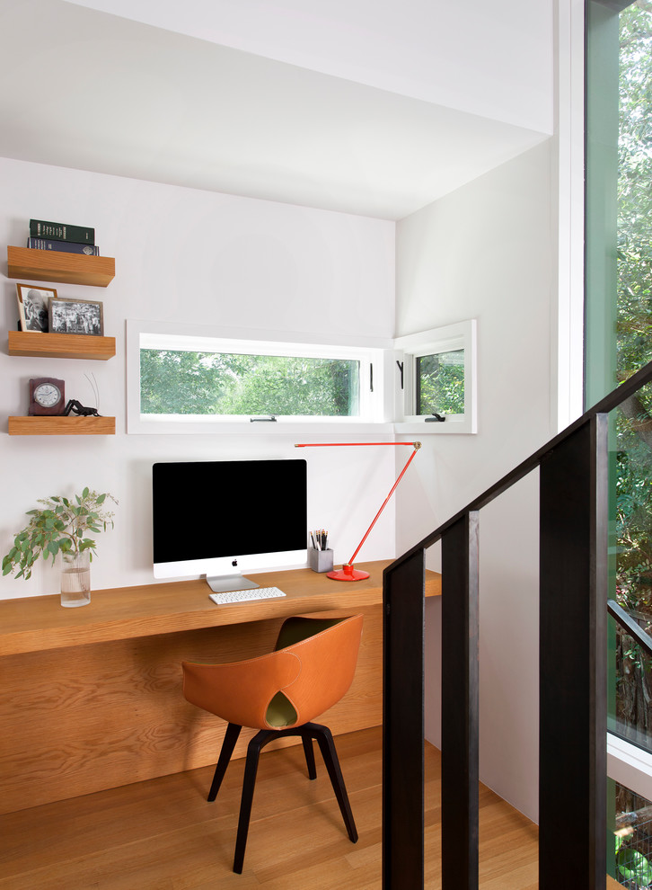 オースティンにある小さなコンテンポラリースタイルのおしゃれなホームオフィス・書斎 (無垢フローリング、暖炉なし、白い壁、造り付け机、茶色い床) の写真