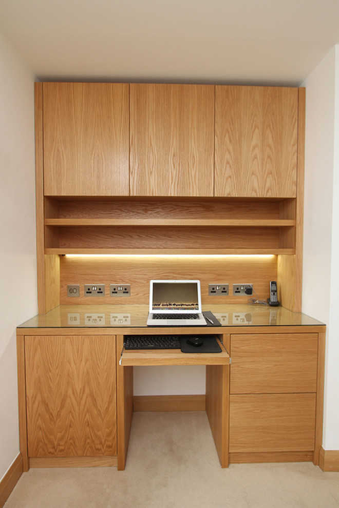 Exempel på ett litet modernt hemmabibliotek, med beige väggar, heltäckningsmatta, ett inbyggt skrivbord och beiget golv