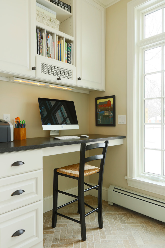 Foto de despacho tradicional renovado pequeño sin chimenea con suelo de piedra caliza, escritorio empotrado y paredes beige