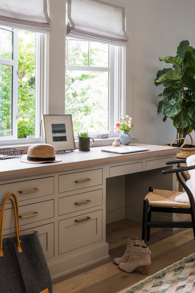 Modelo de despacho tradicional renovado grande con paredes grises, suelo de madera en tonos medios, escritorio empotrado y suelo marrón