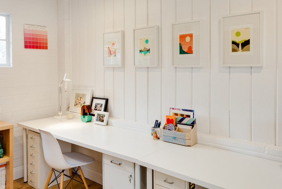 Modelo de despacho clásico renovado de tamaño medio con paredes blancas, escritorio independiente, suelo de madera en tonos medios y suelo marrón