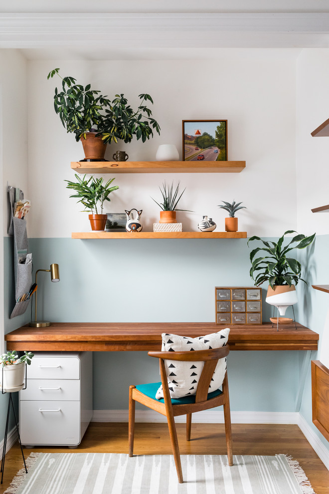 Réalisation d'un bureau ethnique avec un mur bleu, un sol en bois brun, un bureau intégré et un sol marron.