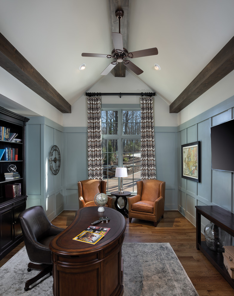 Modelo de despacho clásico con suelo de madera en tonos medios, escritorio independiente y paredes azules