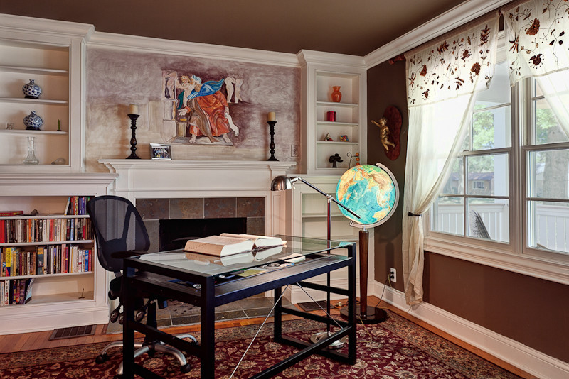 Immagine di un ufficio minimal di medie dimensioni con pareti marroni, camino classico, cornice del camino in pietra, scrivania autoportante e parquet chiaro