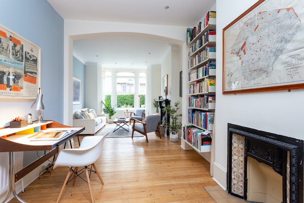 ロンドンにあるトランジショナルスタイルのおしゃれなホームオフィス・書斎 (白い壁、無垢フローリング、両方向型暖炉、自立型机、茶色い床) の写真
