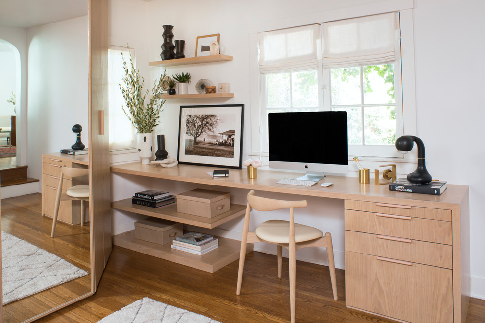 Modernes Arbeitszimmer mit weißer Wandfarbe, braunem Holzboden, Einbau-Schreibtisch und braunem Boden in Los Angeles