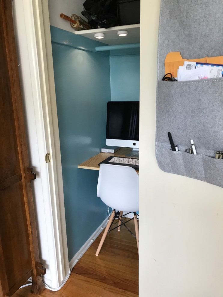 Réalisation d'un petit bureau minimaliste avec un mur bleu, un sol en bois brun, un bureau intégré et un sol marron.