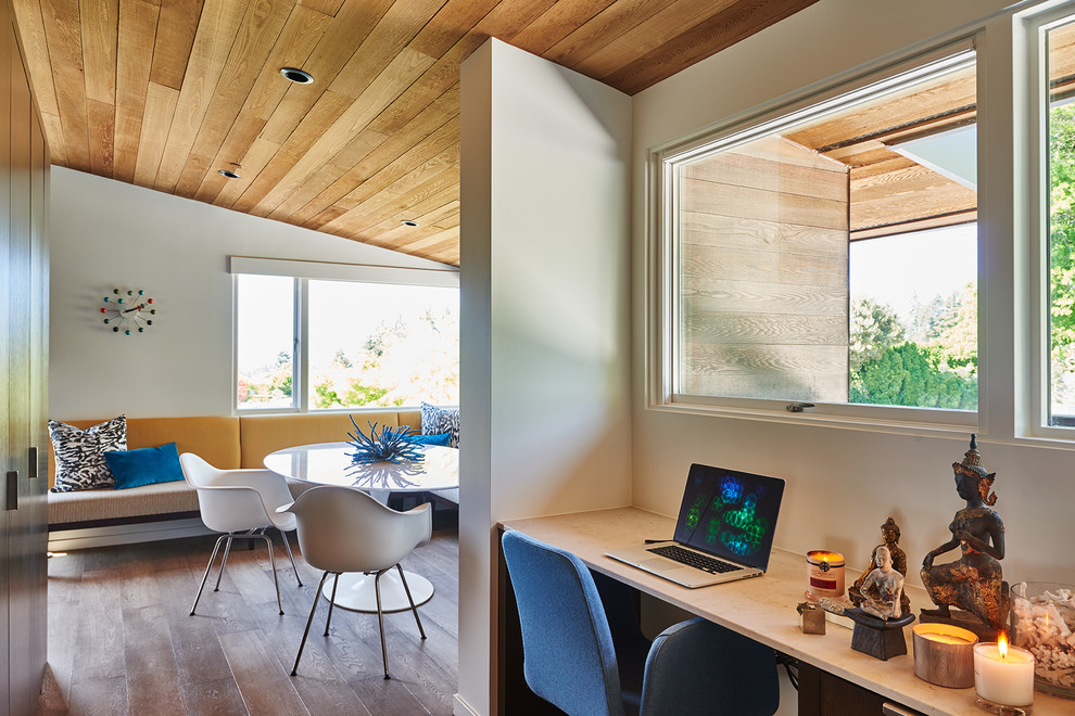 Imagen de despacho retro grande con paredes blancas, suelo de madera en tonos medios y escritorio empotrado