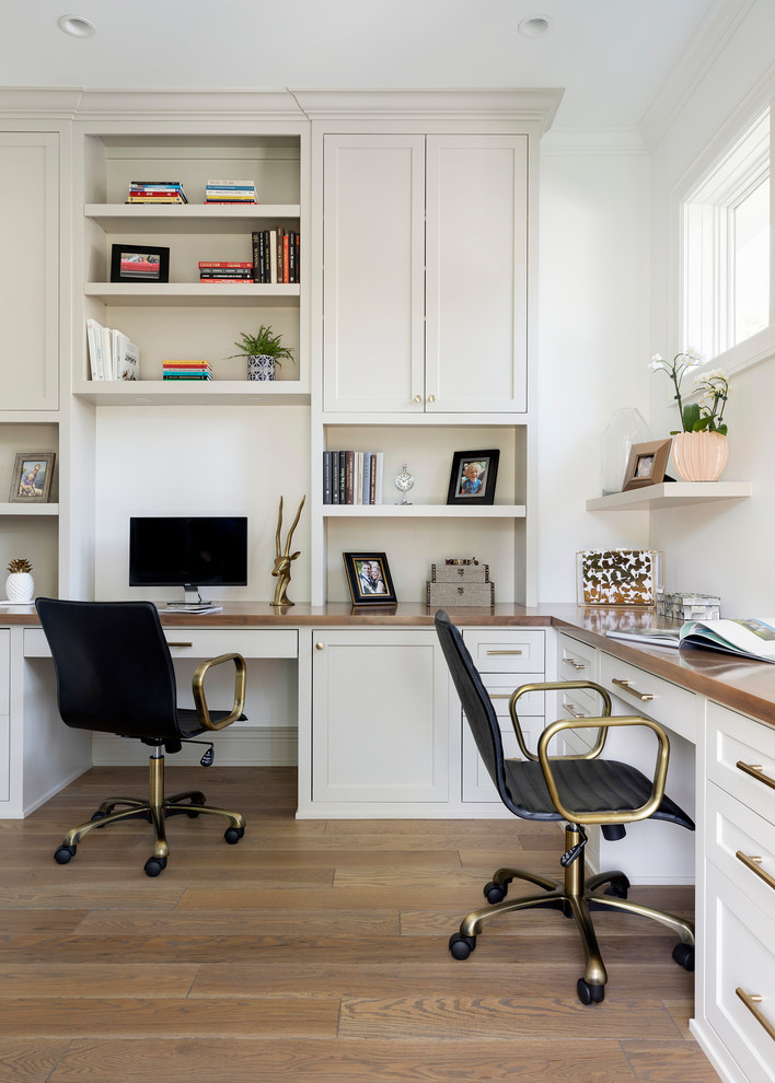 Foto de despacho costero de tamaño medio con paredes blancas, suelo de madera en tonos medios, escritorio empotrado y suelo marrón