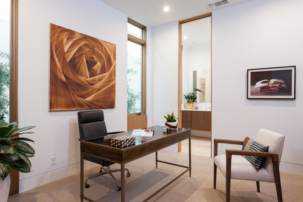 Large contemporary study in Orange County with a freestanding desk, white walls, carpet and beige floors.