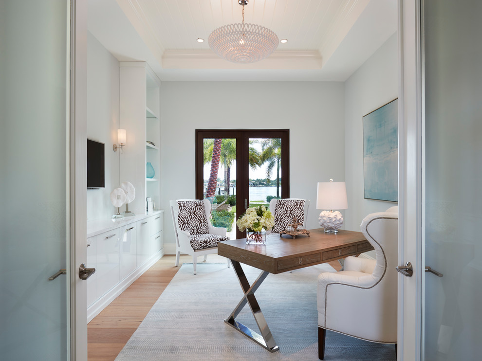 This is an example of a coastal study in Miami with blue walls, light hardwood flooring, a freestanding desk and no fireplace.
