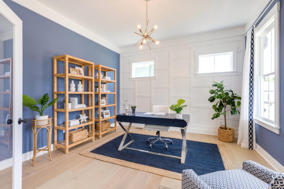 Imagen de despacho costero con paredes blancas, suelo de madera clara, escritorio independiente y suelo beige