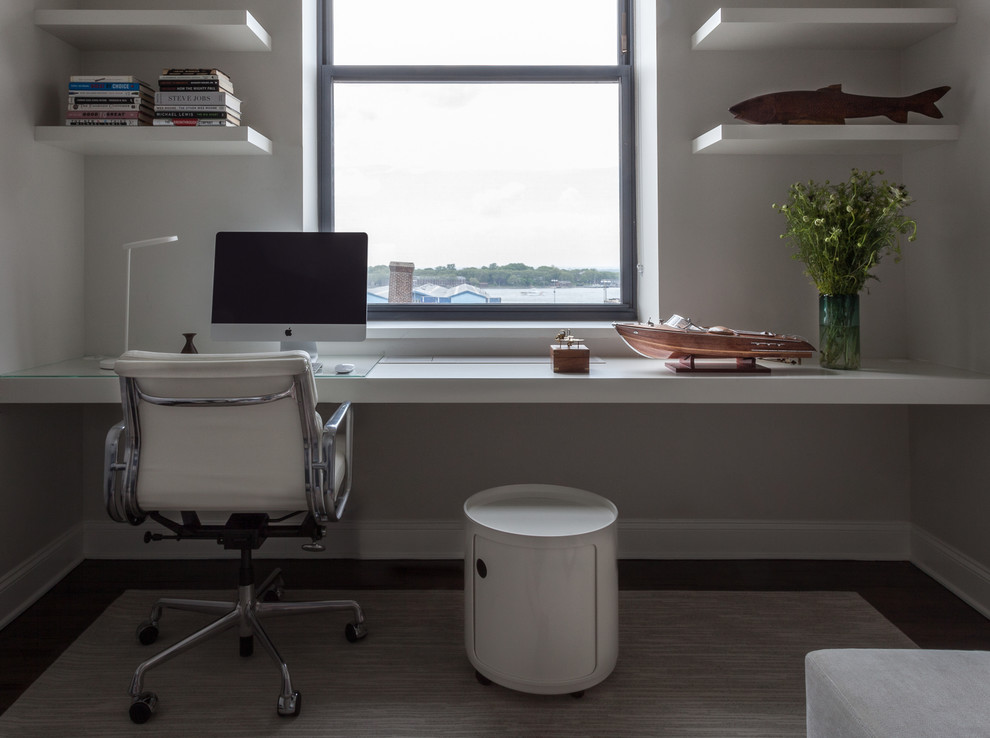 Cette photo montre un grand bureau moderne avec un mur blanc, parquet foncé, un bureau intégré, aucune cheminée et un sol marron.