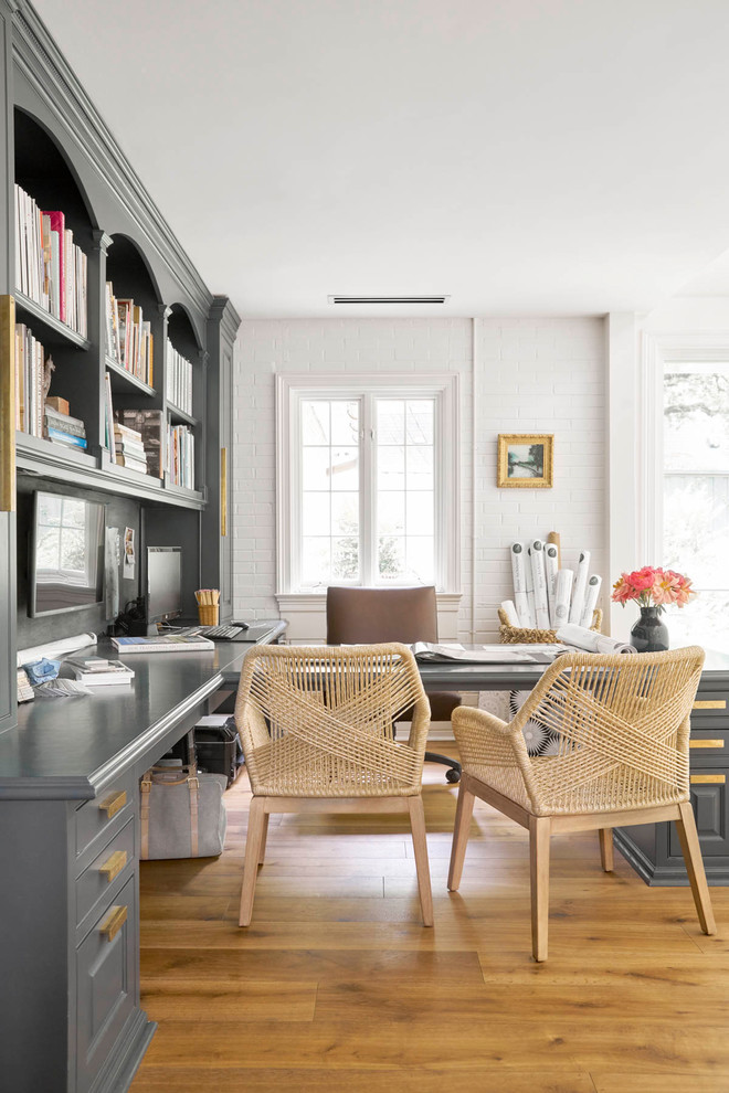 Imagen de despacho clásico renovado con paredes blancas, suelo de madera en tonos medios, escritorio empotrado y suelo marrón
