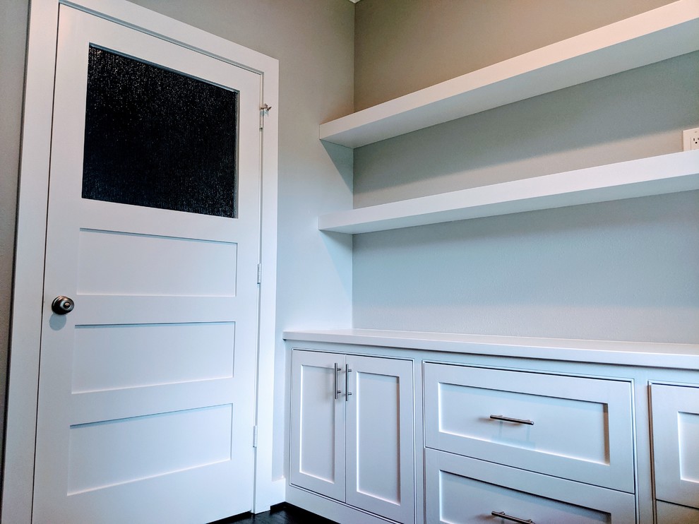 Diseño de despacho abovedado y blanco minimalista grande sin chimenea con paredes grises, escritorio empotrado, suelo de madera oscura y suelo marrón