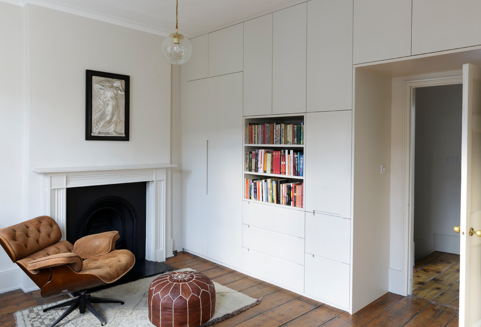 Mittelgroßes Modernes Arbeitszimmer mit weißer Wandfarbe, braunem Holzboden, Kamin und braunem Boden in London