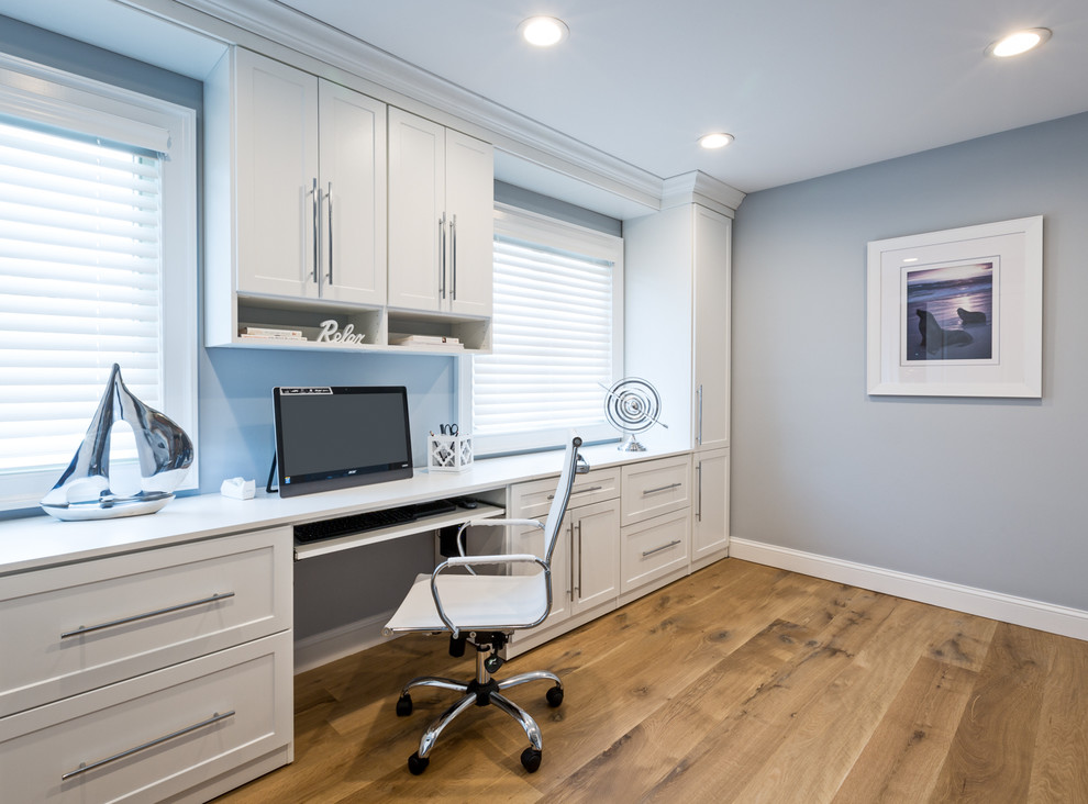 Example of a large trendy built-in desk home office design in New York with gray walls