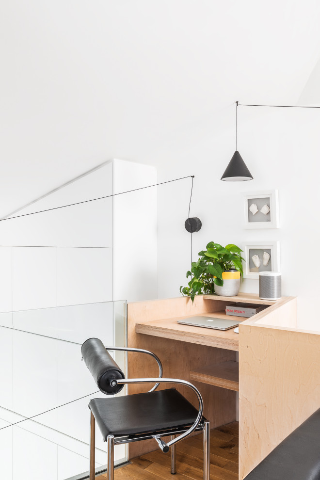 Imagen de despacho actual con paredes blancas, suelo de madera en tonos medios, escritorio empotrado y suelo marrón