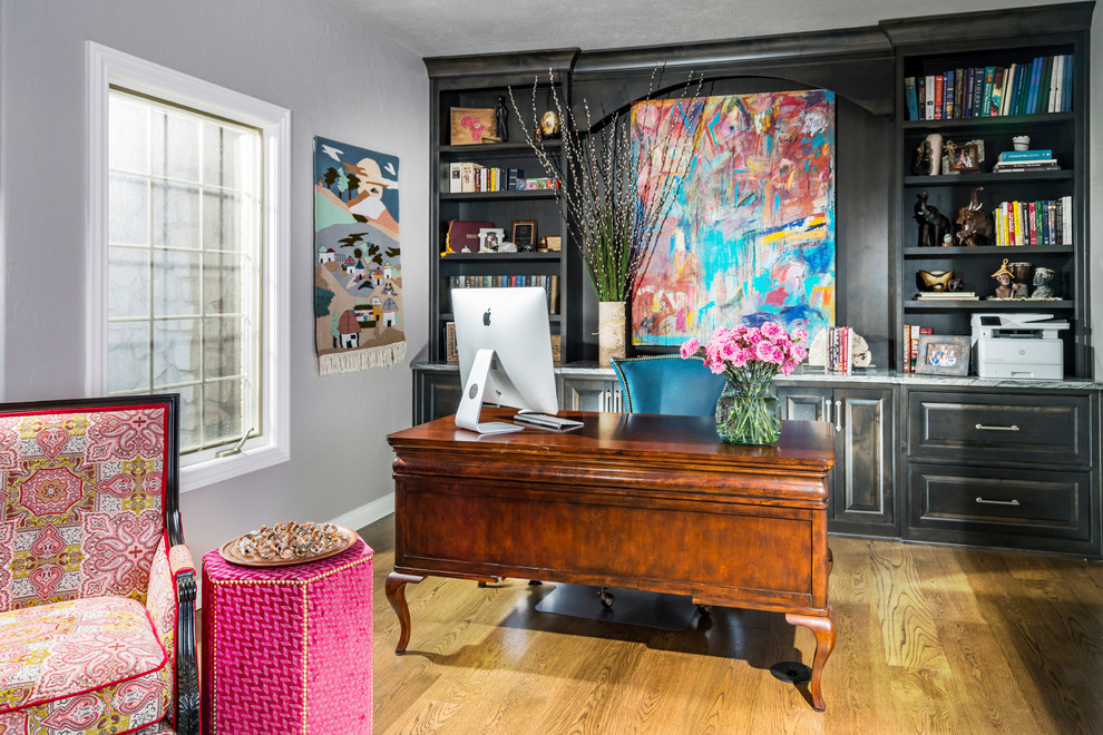 Mittelgroßes Stilmix Arbeitszimmer mit Arbeitsplatz, freistehendem Schreibtisch, grauer Wandfarbe, braunem Holzboden und braunem Boden in Sonstige