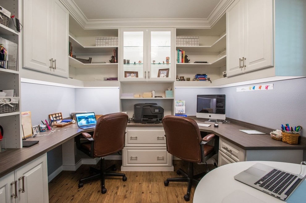Modelo de despacho clásico renovado de tamaño medio sin chimenea con paredes grises, suelo de madera clara, escritorio empotrado y suelo marrón