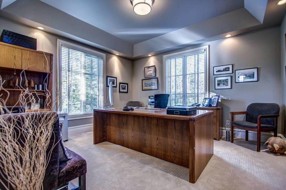 Modelo de despacho de estilo americano de tamaño medio con moqueta, escritorio independiente, suelo beige y paredes grises