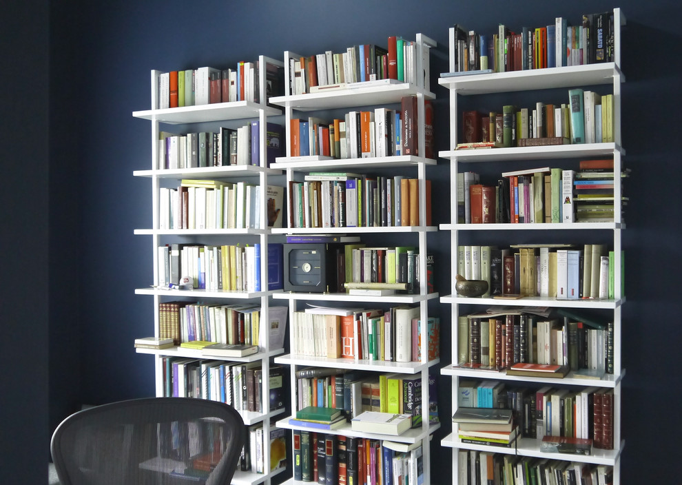 Foto di uno studio minimalista di medie dimensioni con libreria, pareti blu e scrivania autoportante